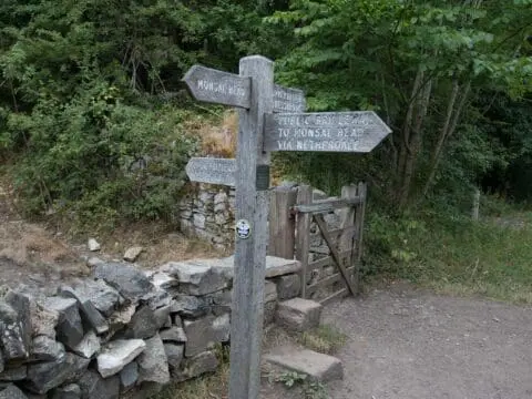 Signposts, gate and stile in a dry stone wall