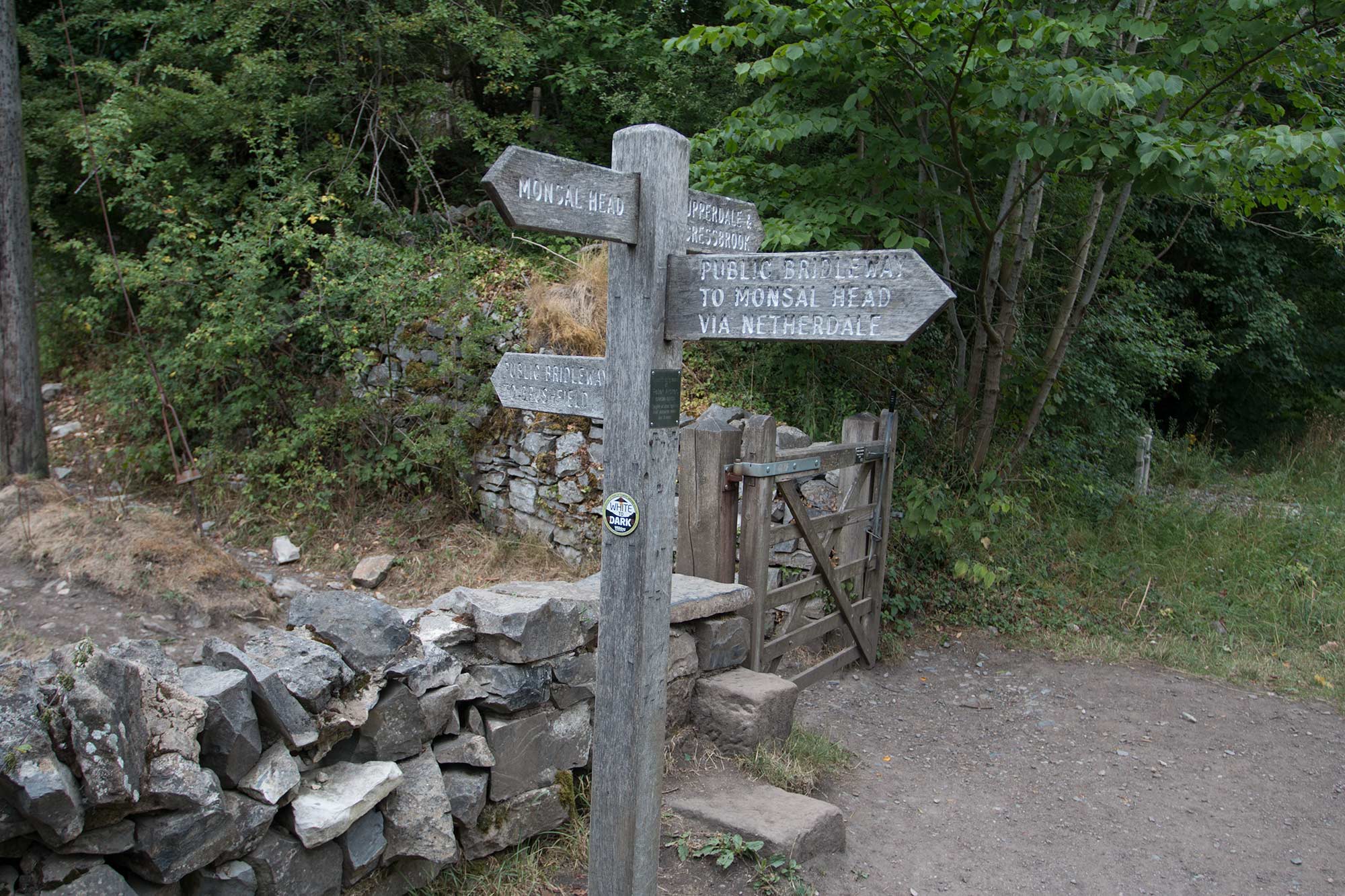 Signposts, gate and stile in a dry stone wall